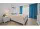 Bright bedroom with a white bed, blue curtains, herringbone wood flooring and beach themed art work at 628 Cleveland St # 711, Clearwater, FL 33755
