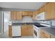 Kitchen with light wood cabinets, stainless steel sink, and white appliances at 6601 13Th N St, St Petersburg, FL 33702