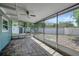 Enclosed porch featuring stone tile flooring, white trim, ceiling fan and views of the back yard and storage shed at 6601 13Th N St, St Petersburg, FL 33702