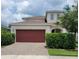 Two-story home featuring a brick driveway, well-maintained landscaping and a red two-car garage door at 7563 Ashcroft Dr, Wesley Chapel, FL 33545