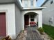 Cozy front porch with a red front door, a cushioned bench and a pathway paved with bricks at 7563 Ashcroft Dr, Wesley Chapel, FL 33545