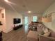 Open-concept living room featuring wood-look flooring, a large sectional and sliding glass doors to the yard at 7563 Ashcroft Dr, Wesley Chapel, FL 33545