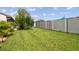 Lush backyard featuring a well-maintained lawn, mature trees, and a privacy fence at 7923 Radcliffe Cir, Port Richey, FL 34668