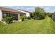 Expansive backyard showcasing vibrant green grass, mature landscaping, and a covered patio area at 7923 Radcliffe Cir, Port Richey, FL 34668