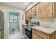 Cozy kitchen with wood cabinetry, stainless steel appliances, and adjacent utility area at 7923 Radcliffe Cir, Port Richey, FL 34668