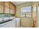 Bright laundry room featuring modern appliances, overhead cabinets, and natural light from the window at 7923 Radcliffe Cir, Port Richey, FL 34668