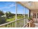 Enclosed balcony with furniture, and plants, overlooking green space, trees, and a pond at 9461 Harbor Greens Way # 502, Seminole, FL 33776