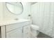 Bright bathroom features a vanity with round mirror, toilet, and decorative shower curtain at 9481 Highland Oak Dr # 1310, Tampa, FL 33647