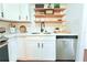 Close-up of white kitchen sink and dishwasher with open wood shelving for decor at 9481 Highland Oak Dr # 1310, Tampa, FL 33647