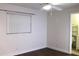 A simple bedroom with dark floors, a ceiling fan, and a small bathroom at 9705 45Th N Way, Pinellas Park, FL 33782