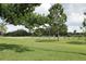 A scenic golf course featuring a vibrant green fairway, mature trees, and a clear blue sky at 9705 45Th N Way, Pinellas Park, FL 33782