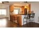 Open kitchen featuring a breakfast bar, wood cabinets, and an adjacent living space with wood-look flooring at 9705 45Th N Way, Pinellas Park, FL 33782