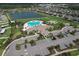 Aerial view showcases the community pool, clubhouse, parking, and serene lake, all nestled amidst lush landscaping at 10308 Malvasia Ave, Riverview, FL 33578