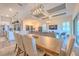 Open-concept dining area with a modern light fixture, wood floors, and adjacent kitchen and living space at 10308 Malvasia Ave, Riverview, FL 33578