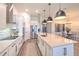 Modern kitchen featuring an island with sleek pendant lighting, white cabinetry, and stainless steel appliances at 10308 Malvasia Ave, Riverview, FL 33578