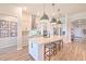 Modern kitchen featuring an island with seating, sleek pendant lighting, stainless steel appliances, and wood flooring at 10308 Malvasia Ave, Riverview, FL 33578