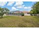 Expansive backyard with screened-in pool, manicured lawn, and beautiful surroundings under a blue sky at 11411 Terrell, Spring Hill, FL 34606