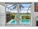 View from inside, looking out through windows to the screened pool with lush landscape, clear blue skies and lake view at 11613 Sunshine Pond Rd, Tampa, FL 33635