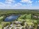 Aerial view of a clubhouse near a pond and golf course, surrounded by trees and lush landscape at 12209 Glencliff Cir, Tampa, FL 33626