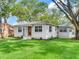 A well-manicured lawn surrounds this home featuring decorative lighting, new landscaping, and a red front door at 1243 55Th N Ave, St Petersburg, FL 33703