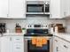 Close-up of a kitchen featuring stainless steel range, microwave, white cabinets and tile backsplash at 1243 55Th N Ave, St Petersburg, FL 33703