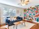 Bright living room featuring a colorful mural, hardwood floors, a ceiling fan, and a cozy blue sofa at 1243 55Th N Ave, St Petersburg, FL 33703