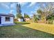Spacious backyard with lush green grass, fencing, and storage sheds at 1415 Yale Dr, Holiday, FL 34691