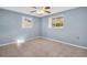Minimalist bedroom featuring neutral tile, light-blue walls, and ample natural light from dual windows at 1415 Yale Dr, Holiday, FL 34691