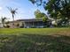 Spacious lawn with mature trees, screened lanai, and landscaped bushes offering backyard privacy at 1510 Flamingo Ln, Sun City Center, FL 33573