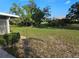 Spacious green backyard with mature trees and side view of home with covered patio at 1510 Flamingo Ln, Sun City Center, FL 33573