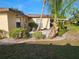 Backyard with a stucco home, palm trees, and small manicured plants at 1510 Flamingo Ln, Sun City Center, FL 33573