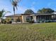 Tan home featuring a screened-in lanai, palm trees, and green grass at 1510 Flamingo Ln, Sun City Center, FL 33573