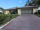 Charming single-story home with a well-maintained lawn, brick driveway, and attached garage at 1510 Flamingo Ln, Sun City Center, FL 33573