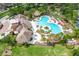 Beautiful aerial shot of the community pool, clubhouse, and lush landscaping, with chairs for lounging at 15403 Wicked Strong St, Sun City Center, FL 33573