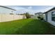 Wide view of the large backyard surrounded by a white fence and green lawn at 15403 Wicked Strong St, Sun City Center, FL 33573
