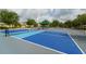 New community pickleball court featuring vibrant blue and gray colors, with shaded benches at 15403 Wicked Strong St, Sun City Center, FL 33573