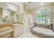 Bright bathroom featuring a soaking tub, glass shower, vanity, and large window view at 1610 Stetson Dr, Wesley Chapel, FL 33543