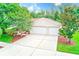Exterior view of a home with a three-car garage, well maintained lawn and mature trees at 1610 Stetson Dr, Wesley Chapel, FL 33543