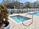 Relaxing hot tub surrounded by paved brick, lush landscaping, and a white fence at 16511 Enclave Village Dr # 107, Tampa, FL 33647