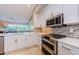 Modern kitchen boasts stainless steel appliances, white cabinets, and mosaic backsplash, showcasing contemporary design and functionality at 1710 Lago Vista Blvd, Palm Harbor, FL 34685