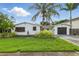 Charming single-story home with tropical landscaping, a driveway, and a one-car garage at 1720 Bayou Grande Ne Blvd, St Petersburg, FL 33703