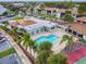 Community pool and clubhouse surrounded by lush landscaping, tennis courts, and parking at 1967 Cormorant Ct # 515, Clearwater, FL 33762