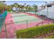 Outdoor tennis court with green surface and fencing surrounded by trees and greenery at 1967 Cormorant Ct # 515, Clearwater, FL 33762