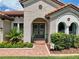 Close-up of the front door featuring decorative wreaths, arched windows, and manicured landscaping at 3236 Barbour Trl, Odessa, FL 33556