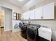 Spacious laundry room featuring modern appliances, white cabinets, a utility sink, and stylish wood-look flooring at 3236 Barbour Trl, Odessa, FL 33556