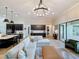 Open-concept living room with modern chandelier, large sectional sofa, and view to kitchen at 3236 Barbour Trl, Odessa, FL 33556