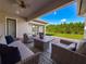 Relaxing covered patio featuring comfortable seating, a modern fire pit, and access to the lush green backyard at 3236 Barbour Trl, Odessa, FL 33556