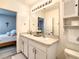 Bathroom featuring double sinks, a large mirror with vanity lighting, and a cabinet for extra storage at 32977 Kaloko Rd, Wesley Chapel, FL 33543