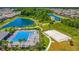 Aerial view of a sparkling pool, amenity center, sidewalks, basketball court and scenic ponds surrounded by lush greenery at 32977 Kaloko Rd, Wesley Chapel, FL 33543