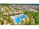 Aerial view of a stunning community pool with sun loungers, covered seating areas, palm trees, and lush landscaping at 32977 Kaloko Rd, Wesley Chapel, FL 33543